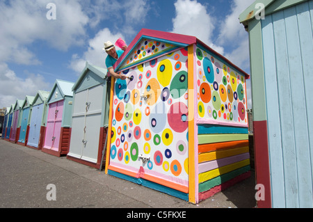 Un uomo di mezza età sfidando le regole e dipinto il suo Brighton Beach Hut in non-regolamento macchie colorate. Foto Stock