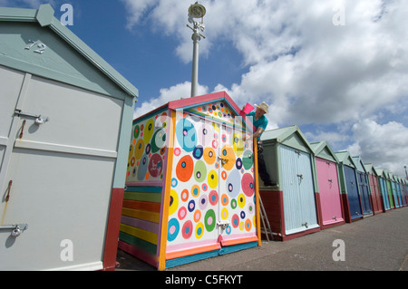 Uno dispari. Un ribelle beach hut si distingue da un dipinto uniformemente fila. Foto Stock