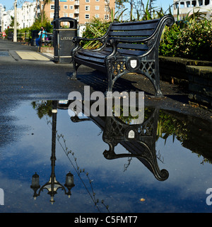 Un lampione e panca riflessa in una pozza su una mattina d'estate. Foto di Julie Edwards Foto Stock