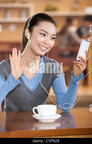 Excited donna giovane ascoltare musica ad un coffee shop Foto Stock