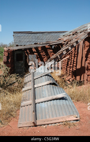 Il tetto di uno sbriciolamento stucco e mattoni di fango farm house si trova dietro la casa in Cuervo New Mexico. Foto Stock