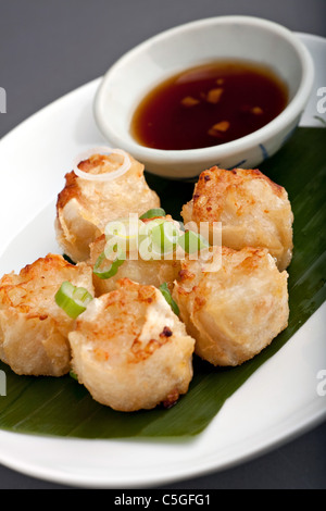 Fritti antipasti tailandese con soia Salsa di immersione presentato su una piastra con foglia di banano e scalogno guarnire. Foto Stock