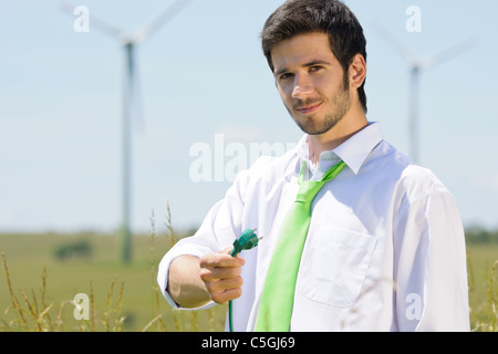 Energia verde - il giovane imprenditore tenere il tappo nel campo con il mulino a vento Foto Stock