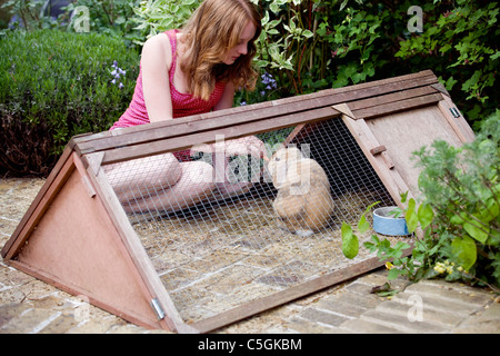 Una giovane ragazza alimentando il suo animale domestico coniglio in giardino Foto Stock