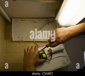 Elettricista qualificato installazione  Installazione di una luce di emergenza Foto Stock