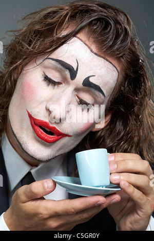 Ritratto di uomo con faccia dipinta holding tazza da caffè Foto Stock