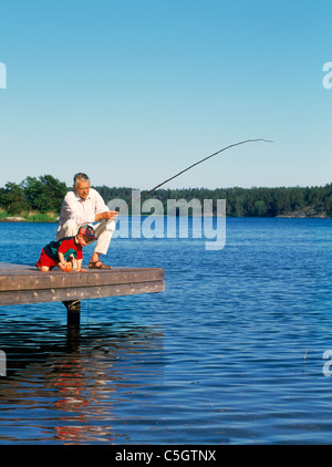 La pesca del nonno con il nipote off dock in legno lungo il Mar Baltico litorale durante l estate svedese Foto Stock