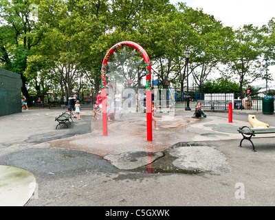 Giocare i bambini giocando in ugelli di spruzzo acqua caratteristica di DeWitt Clinton park di Hells Kitchen quartiere di New York City Foto Stock