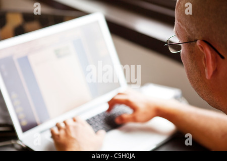 Uomo che utilizza un computer portatile per interni Foto Stock