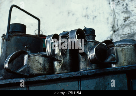 Lattine di olio su un ripiano in un capannone del motore utilizzata per il ripristino di motori a vapore Foto Stock