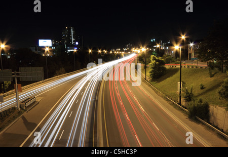 Veicoli in movimento crea percorsi di luce durante una lunga esposizione di una autostrada di notte. Foto Stock