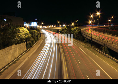 Veicoli in movimento crea percorsi di luce durante una lunga esposizione di una autostrada di notte. Foto Stock