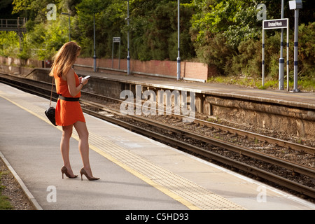 Giovane donna in attesa di un treno, Elmstead Woods, stazione treni sud-orientale, London REGNO UNITO Foto Stock