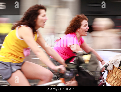 Due donne che si avvicinano alla linea di finitura della British Heart Foundation Londra a Brighton in bicicletta 2011 - sfocatura del movimento Foto Stock