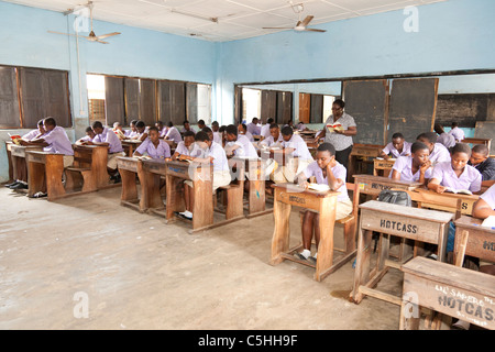 Studenti delle scuole secondarie in uniforme che lavorano alle scrivanie in classe, Accra, Ghana Foto Stock