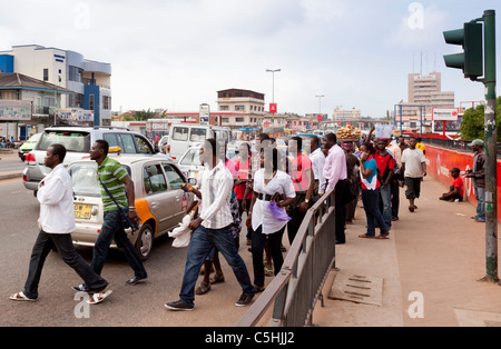 Le persone che attraversano una strada trafficata in ora di punta. Accra, Ghana Foto Stock