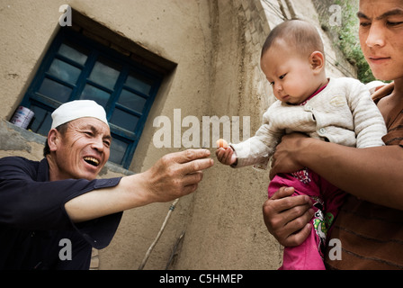 Contadino dando un mingherlino albicocca a suo nipote, Ningxia, Cina Foto Stock