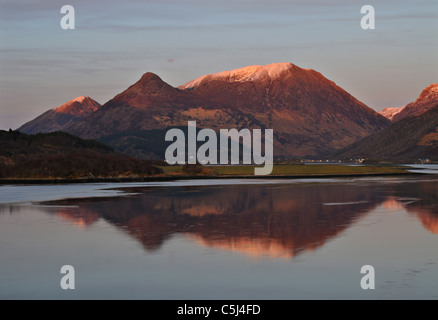 Serata calda luce sulle calme acque del Loch Leven e lo snow-capped Glencoe colline, Glencoe, Argyll, Scozia occidentale Foto Stock