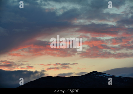 Rosso tramonto nuvole sopra un ombroso Trangdale mountain, a nord-ovest della Norvegia. Foto Stock