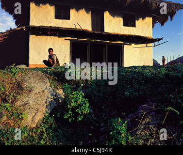 Due piccole figure umane accanto a un quasi-eseguita la nuova casa del villaggio di Num nel fiume Arun regione est del Nepal Foto Stock