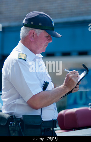 Un vigile la scrittura di un biglietto per un illegalmente parcheggiato l'auto. Stratford su Avon. Regno Unito Foto Stock