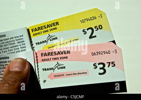 Mano che tiene libri di Translink una zona di due bus faresaver e luce di transito rapido di biglietti per la metropolitana Vancouver BC Foto Stock