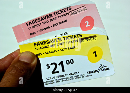 Mano che tiene libri di Translink una zona di due bus faresaver e luce di transito rapido di biglietti per la metropolitana Vancouver BC Foto Stock
