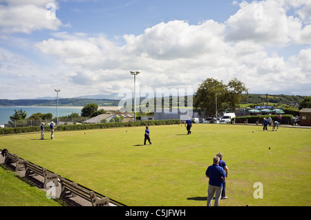 Benllech, Isola di Anglesey, Galles del Nord, Regno Unito. Persone a giocare a bocce in bowling green con vista sulla costa Foto Stock