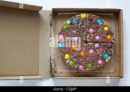 Il cioccolato bianco pizza con trefoli di cioccolato e smarties in scatola aperta per mostrare i contenuti Foto Stock