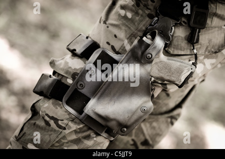 Pistola nella fondina sul commando soldato è la gamba Foto Stock