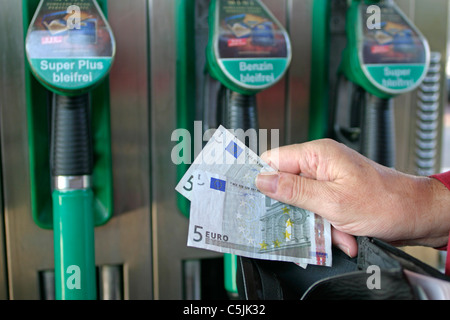 Un uomo contando il suo denaro in corrispondenza di una stazione di benzina Foto Stock