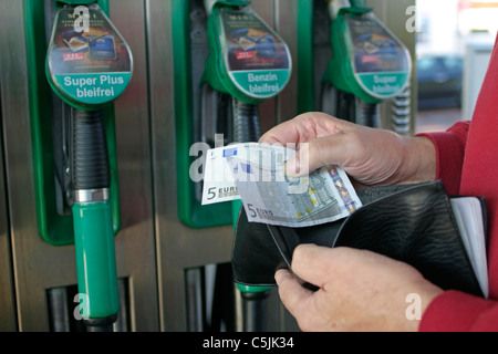 Un uomo contando il suo denaro in corrispondenza di una stazione di benzina Foto Stock