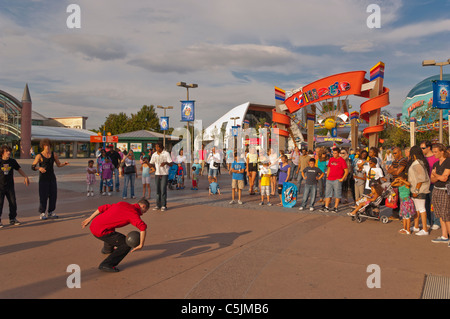 Un esecutore di strada musicista di strada al di fuori dell'entrata al Villaggio Disney a Disneyland Paris in Francia Foto Stock