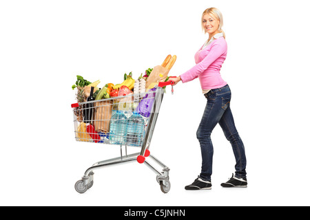 Un giovane femmine spingendo un carrello pieno di negozi di generi alimentari Foto Stock