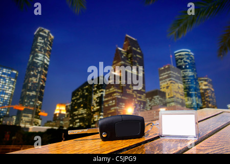 Autonoleggio chiavi sul tavolo di legno con carta bianca nella notte di Houston Downtown Foto Stock