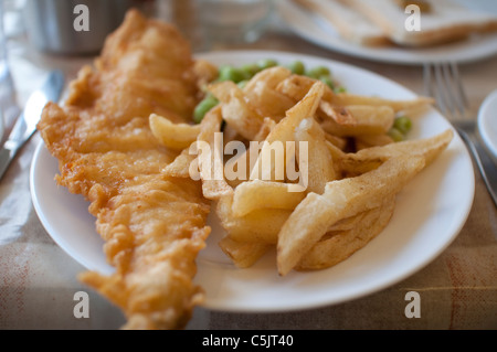 Pesce e patatine fritte servite con fiacco piselli su una piastra in Inghilterra. Foto Stock