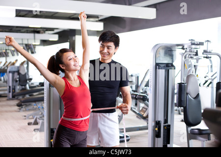 Giovane uomo misura di giovane donna alla Palestra Foto Stock
