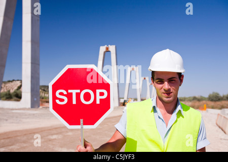 Un operaio di arresto del traffico di costruzione dove la ferrovia attraversa una strada in corrispondenza di un collegamento ferroviario ad alta velocità essendo costruito Foto Stock