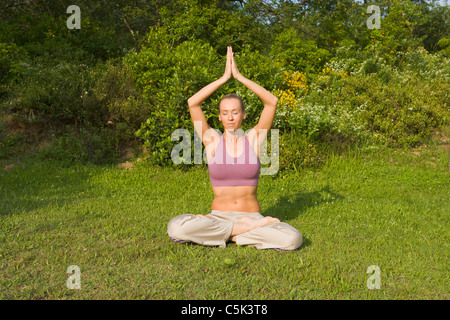 Giovane donna in metà Lotus Yoga pongono (MR) Foto Stock