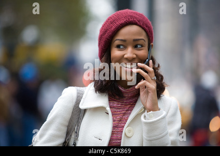 Un attraente business donna colloqui sul suo telefono cellulare come lei cammina attraverso la città. Foto Stock