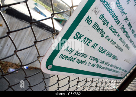 Un segno a skate park afferma chiaramente che potrete pattinare a proprio rischio. Profondità di campo. Foto Stock