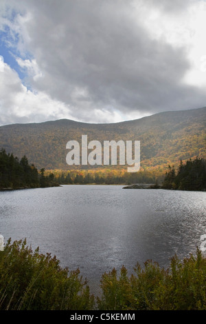 Piccolo lago ai piedi di montagne in Autunno a colori. Foto Stock