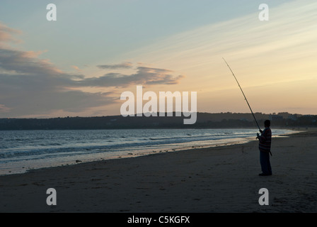 Pescatore solitario sulla spiaggia Foto Stock