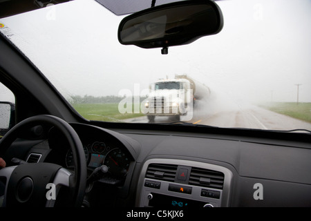 Car guida attraverso la pioggia torrenziale e allagamento con carrello che sopraggiungono nel sud del Saskatchewan canada Foto Stock