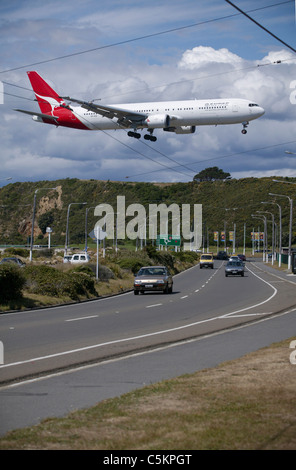 Boeing 767 aereo di linea della Qantas Airways in arrivo ad atterrare all'aeroporto internazionale di Wellington, Nuova Zelanda, volando a bassa quota sopra la strada Foto Stock