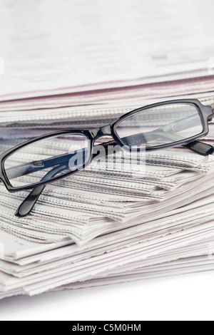 Un mucchio di giornali e un paio di occhiali da lettura Foto Stock