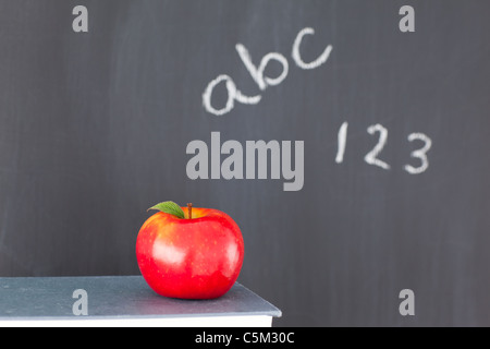 Libri un Apple e le cifre e lettere scritte su una lavagna Foto Stock