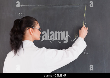 Dai capelli scuri disegno dello scienziato un grafico sulla lavagna Foto Stock