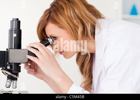 Attraente scienziato bionda guardando attraverso un microscopio Foto Stock