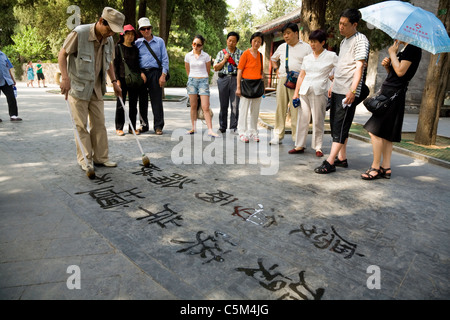 Busker che espone l'arte della calligrafia con scrittura d'acqua di caratteri cinesi con 'pennelli dell'inchiostro' ai turisti al Palazzo d'Estate a Pechino, Cina. (61) Foto Stock